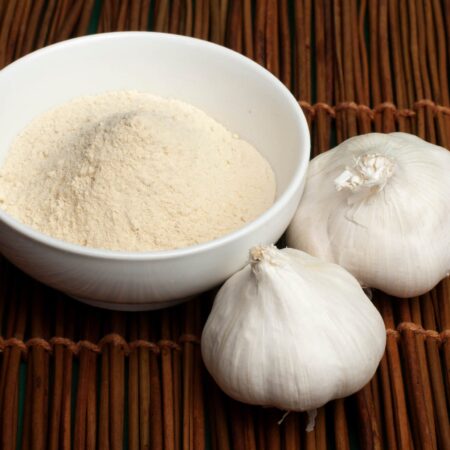 Miska sušeného cesnaku v prášku a dva cesnakové strúčiky