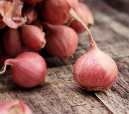 Detailná fotografia šalotiek na drevenom povrchu.