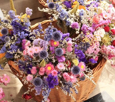 Kôš plný farebných sušených kvetov, vrátane modrých, ružových a fialových odtieňov, pripravených na výrobu dekorácií.