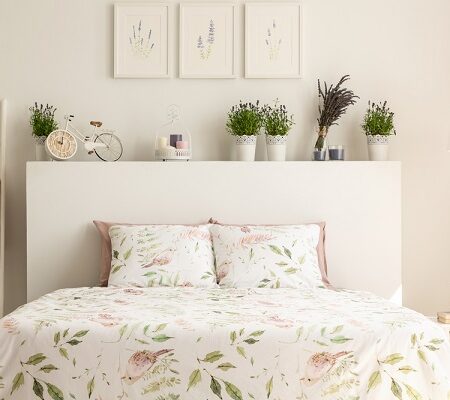 Elegantná spálňa s kvetinovou posteľou s bielizňou a dekoráciami na bielom pozadí.