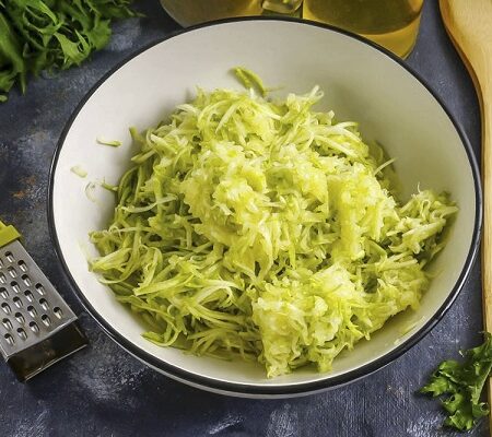 Strúhaná cuketa pripravená na prípravu cuketových špagiet v bielej miske.