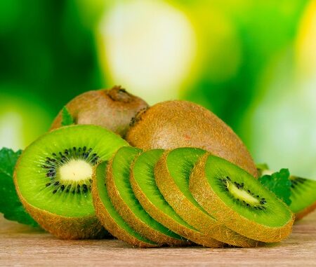 Účinky kiwi na zdravie, rozkrájané kiwi na zelenom pozadí.