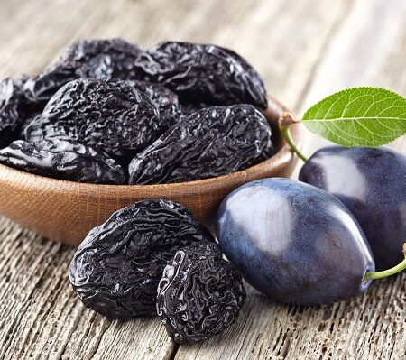 Ako sušiť slivky. Miska sušených sliviek vedľa čerstvých sliviek na drevenom stole.