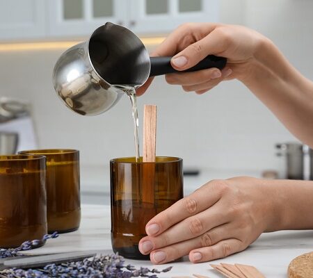 Levanduľová sviečka. Nalievanie roztopeného vosku do skleneného pohára s dreveným knôtom na výrobu domácej sviečky.