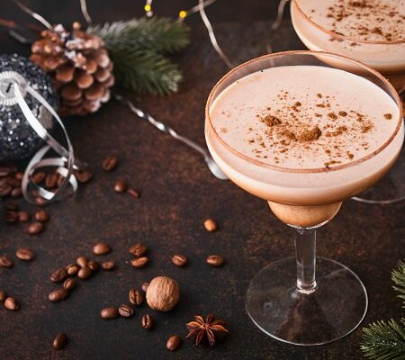 Elegantné kávové koktaily s posypom škorice, podávaný v sklenenom pohári na sviatočnom stole s vianočnou výzdobou.