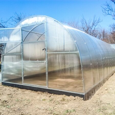 Príprava skleníka. Moderný polykarbonátový skleník na záhrade pripravený na jarné pestovanie zeleniny.