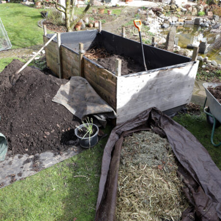 Lasagne záhrada, Príprava lasagne záhrady s vrstvami organického materiálu, kompostom, zeminou a slamou vo vyvýšenom záhone v záhradnom prostredí.