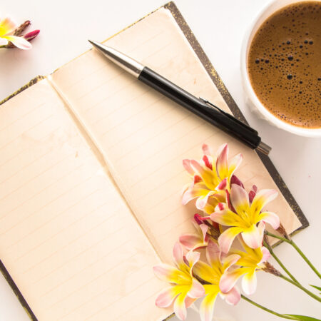 Záhradný denník – otvorený zápisník s perom, kávou a kvetmi na plánovanie výsadby