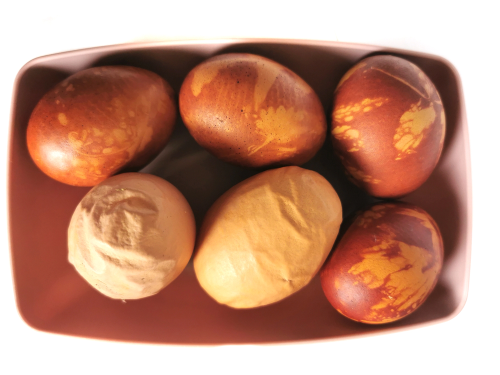 Ukážka tradičného farbenia veľkonočných vajíčok pomocou cibuľových šupiek a rastlinných listov, ktoré zanechávajú jemné a prirodzené ornamenty.