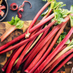 Čerstvé stonky rebarbory na drevenej doske – surovina známa pre rebarbora a jej účinky na zdravie