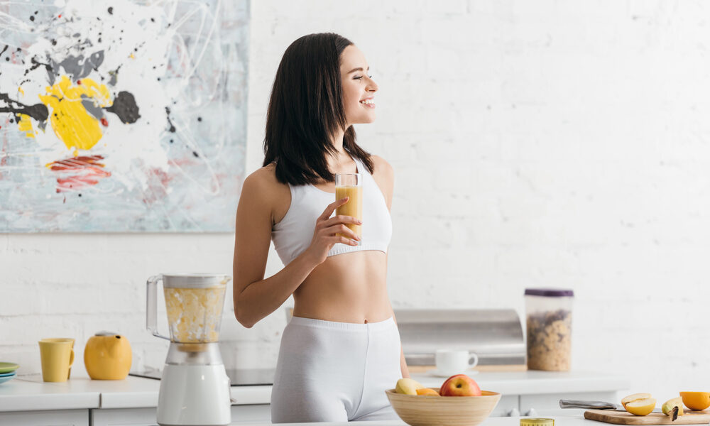 žena v kuchyni pije zdravý zoštíhľujúce nápoje z ovocia pripravený v mixéri