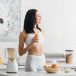 žena v kuchyni pije zdravý zoštíhľujúce nápoje z ovocia pripravený v mixéri