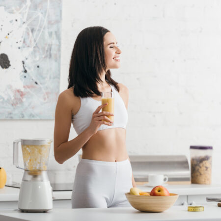 žena v kuchyni pije zdravý zoštíhľujúce nápoje z ovocia pripravený v mixéri