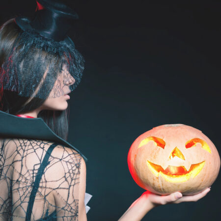 Najstrašidelnejšie miesta na Halloween – žena v kostýme s vyrezávanou svietiacou tekvicou